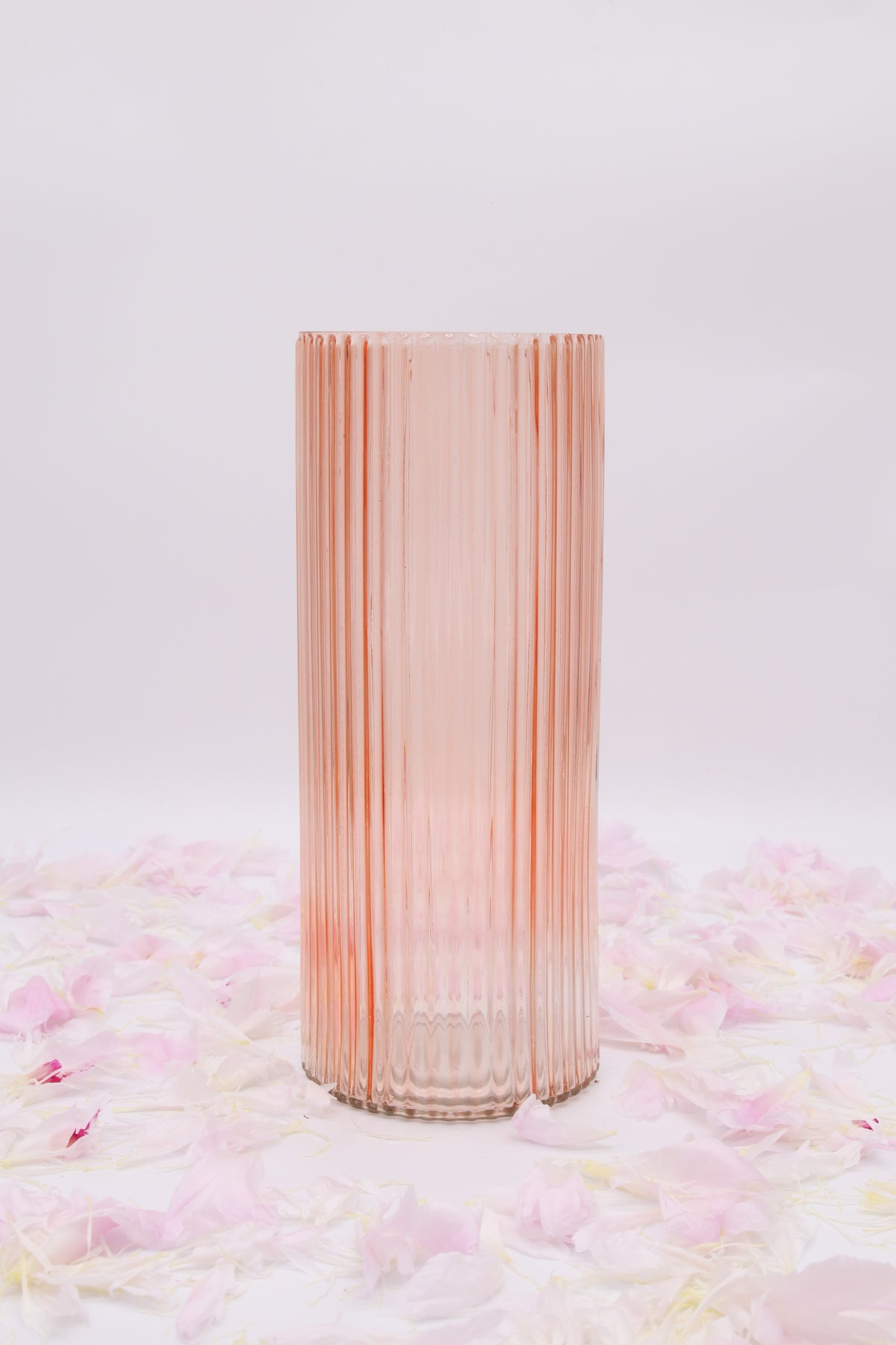 Vase cylindrique rose seul, en verre transparent à fines côtes verticales.