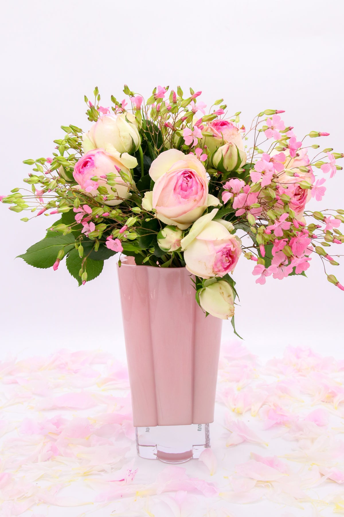 Vase Larissa rose à reliefs verticaux, présenté avec un bouquet de roses roses et blanches.
